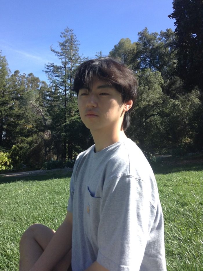 Hong Ju Jin sitting on the grass outdoors on a sunny day